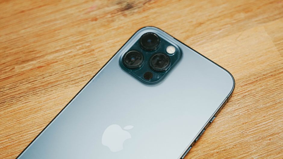 Gambar close-up smartphone ramping dengan kamera tiga di permukaan kayu.