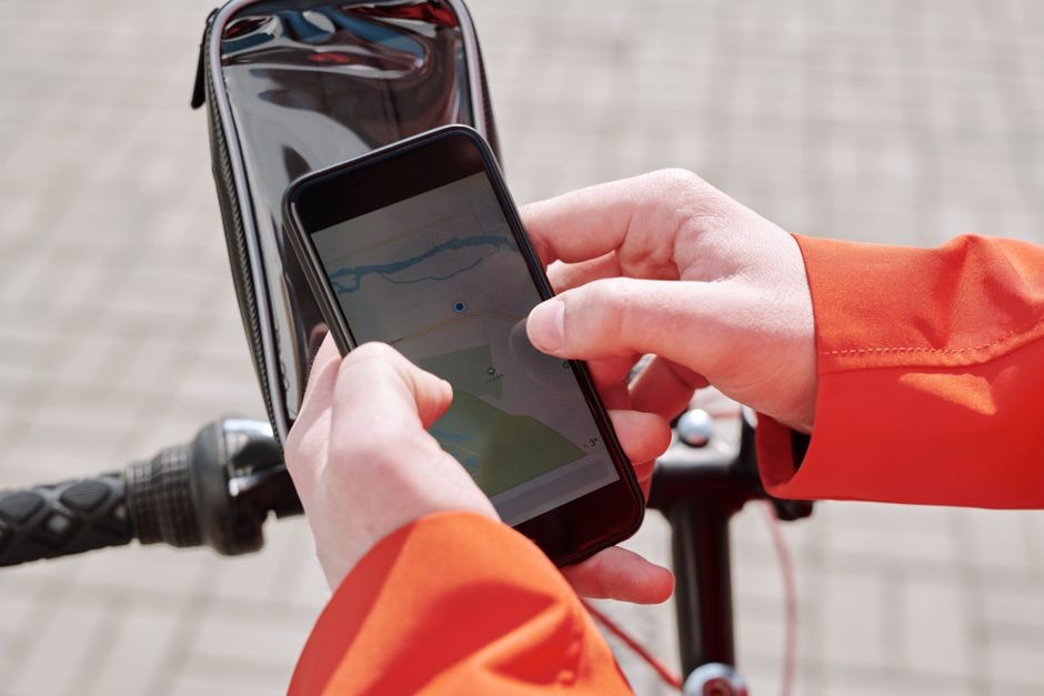 Tangkapan dekat pesepeda menggunakan aplikasi navigasi GPS smartphone yang dipasang di sepeda di luar ruangan.