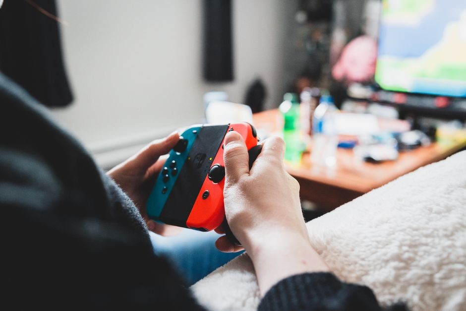 Close-up seseorang yang bermain video game dengan pengontrol nirkabel. Aktivitas rekreasi di dalam ruangan.
