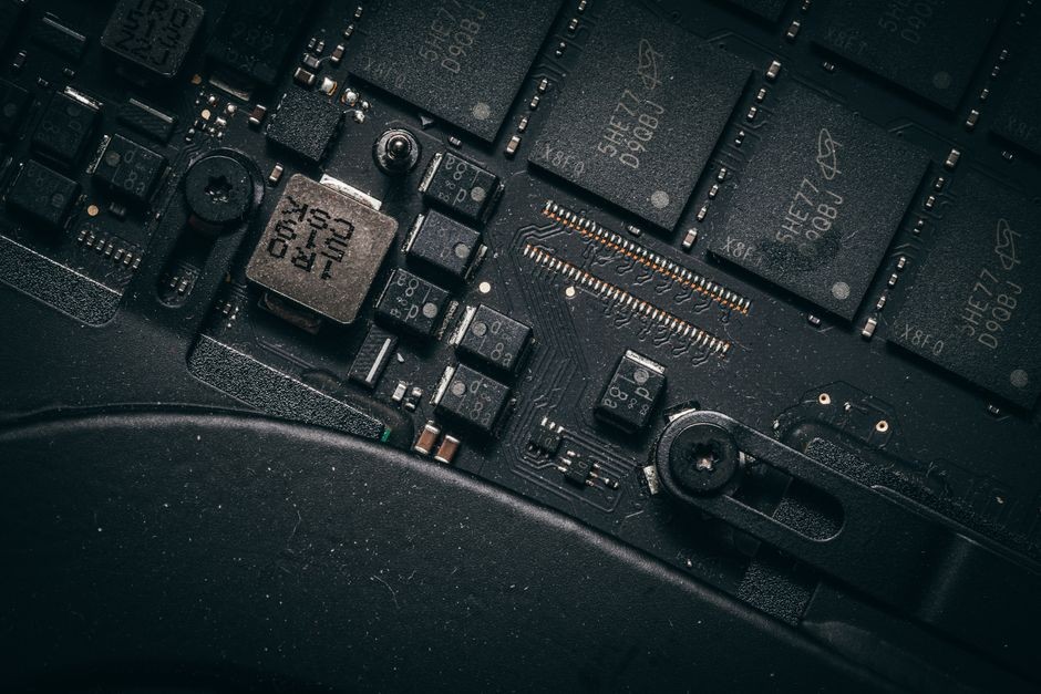 Foto makro detail dari papan sirkuit elektronik yang menunjukkan mikrochip dan komponen-komponennya.