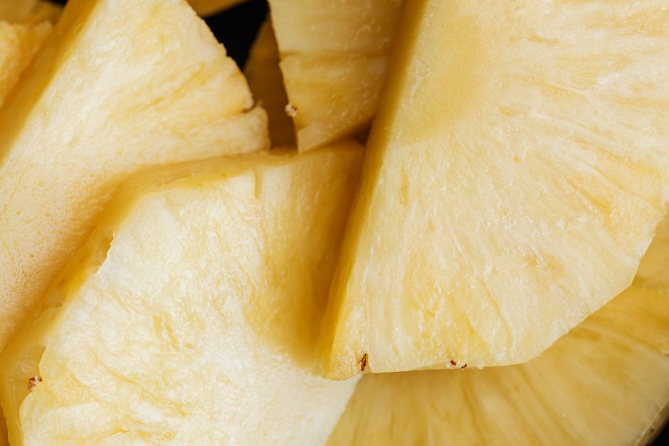 Tutup dekat potongan nanas segar dan juicy yang diambil dari atas, menampilkan warna kuning cerahnya.