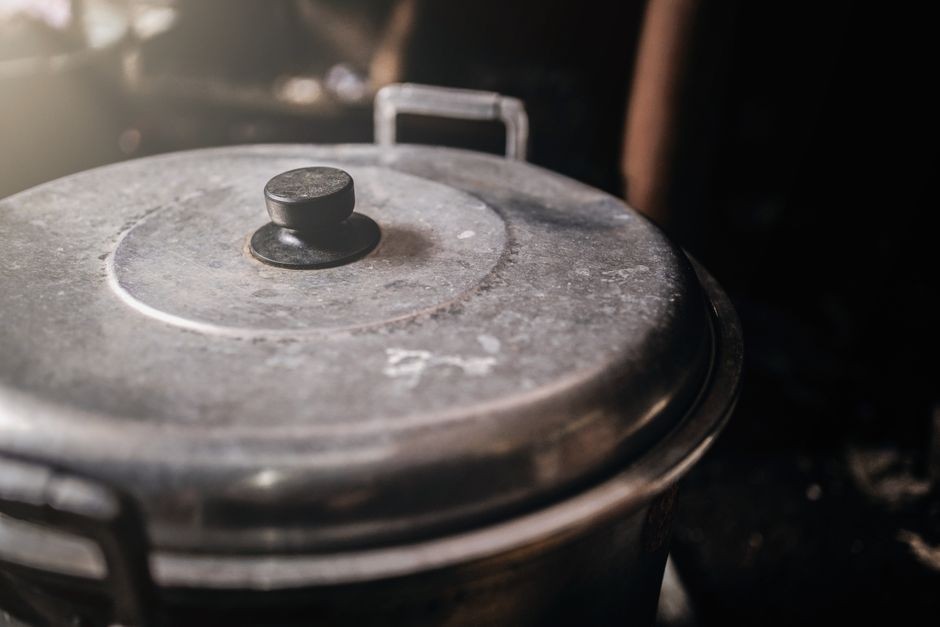 Proses memasak kuah sayur di atas kompor dapur menggunakan panci logam