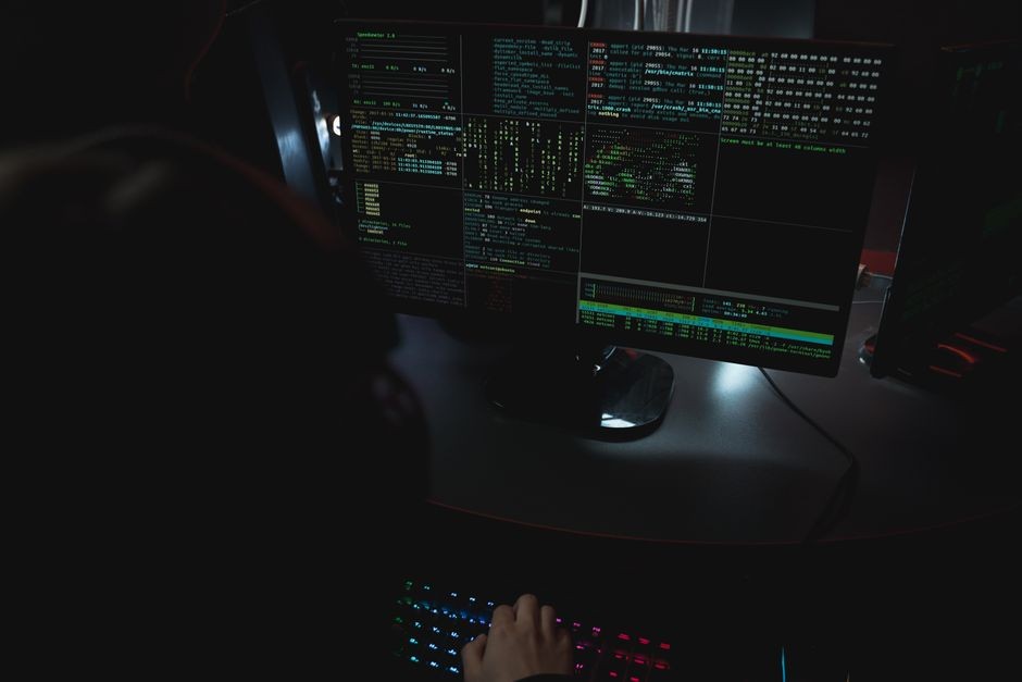Tangan mengetik di atas keyboard dengan layar gelas berisi kode dan antarmuka peretasan