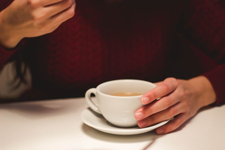 Seseorang menikmati secangkir kopi dengan santai di meja kerja yang terang