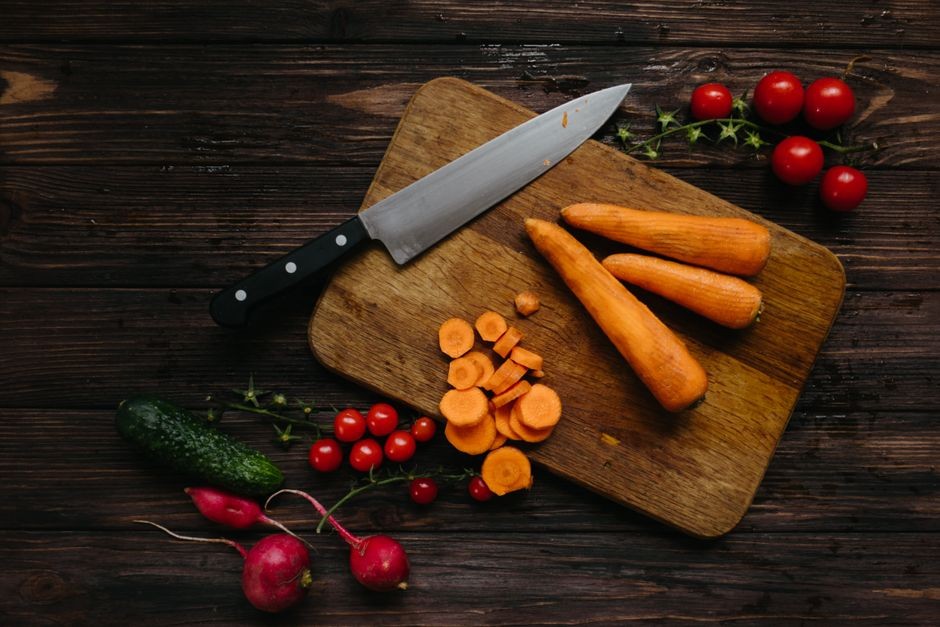 Pengambilan gambar dari atas sayuran segar dan pisau dapur di papan kayu.