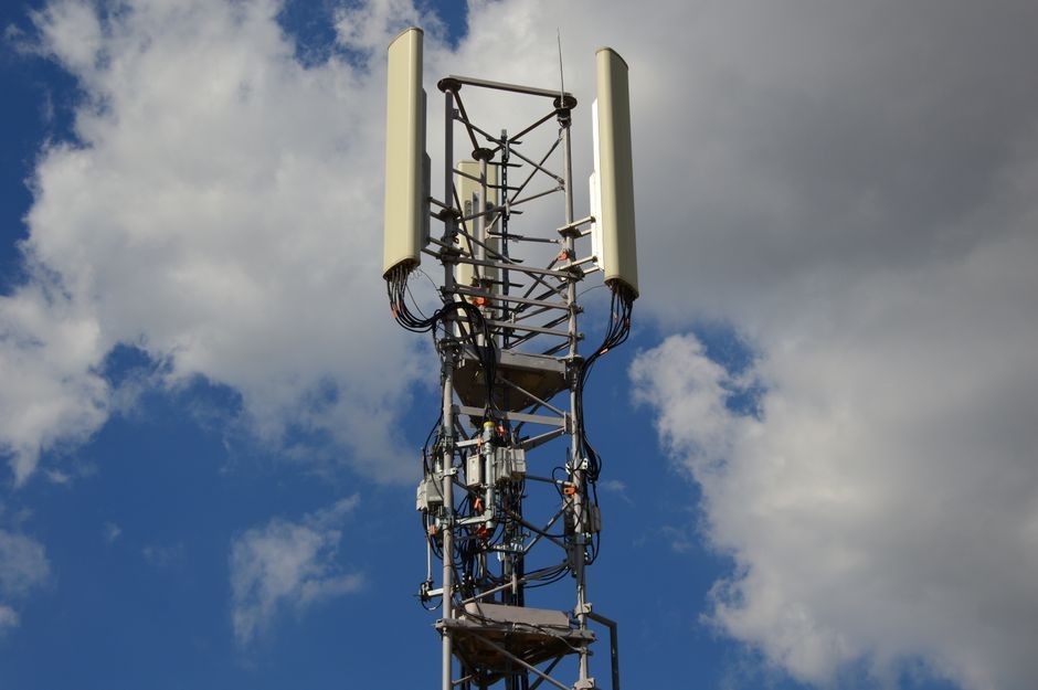 Menara jaringan seluler 5G berdiri di area perumahan dengan langit sore