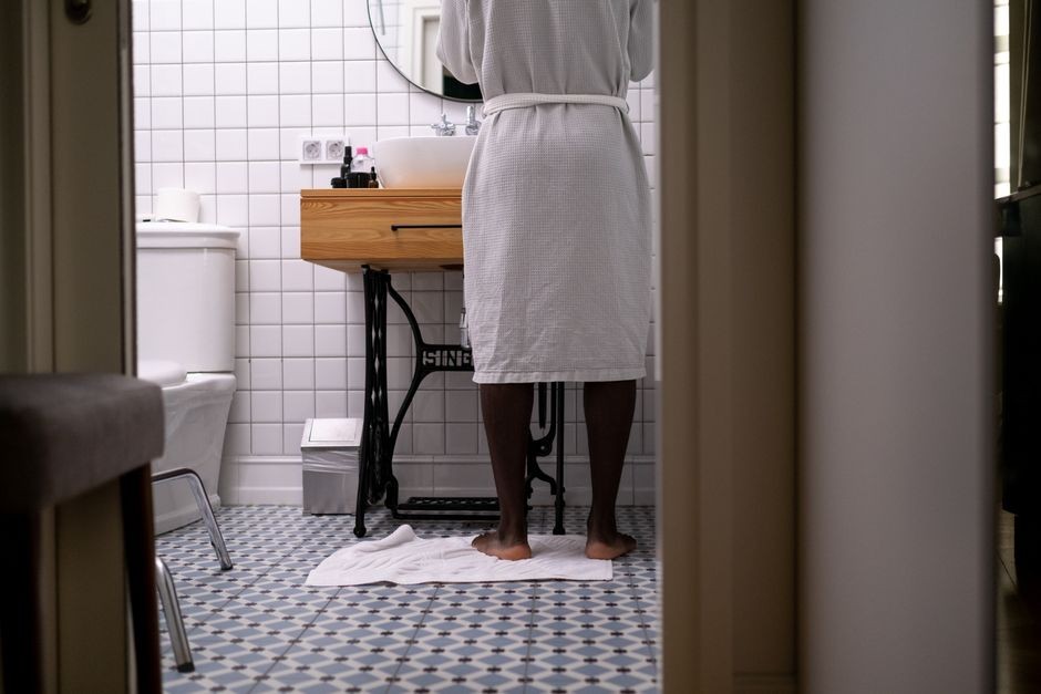 Lantai kamar mandi berkeramik yang basah dengan keset lembap di dekat shower