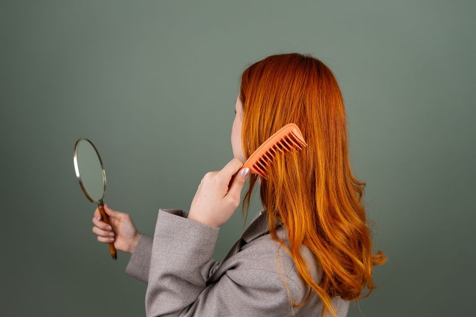 Wanita sedang menyisir rambut di depan cermin di rumah