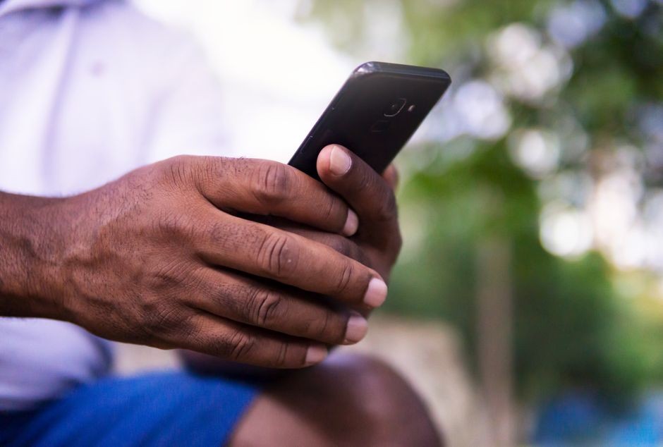 Tangan pengguna mengetik di smartphone saat mempersiapkan pembaruan sistem