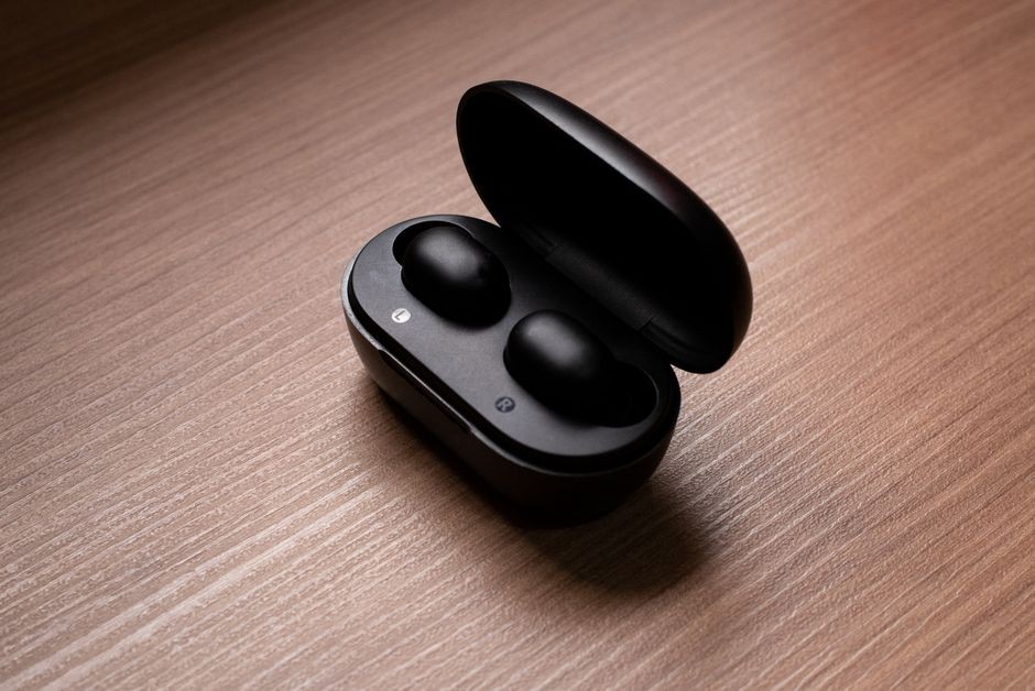 Sepasang TWS dan headset berada di atas meja kerja, ilustrasi tingkat volume aman untuk pendengaran