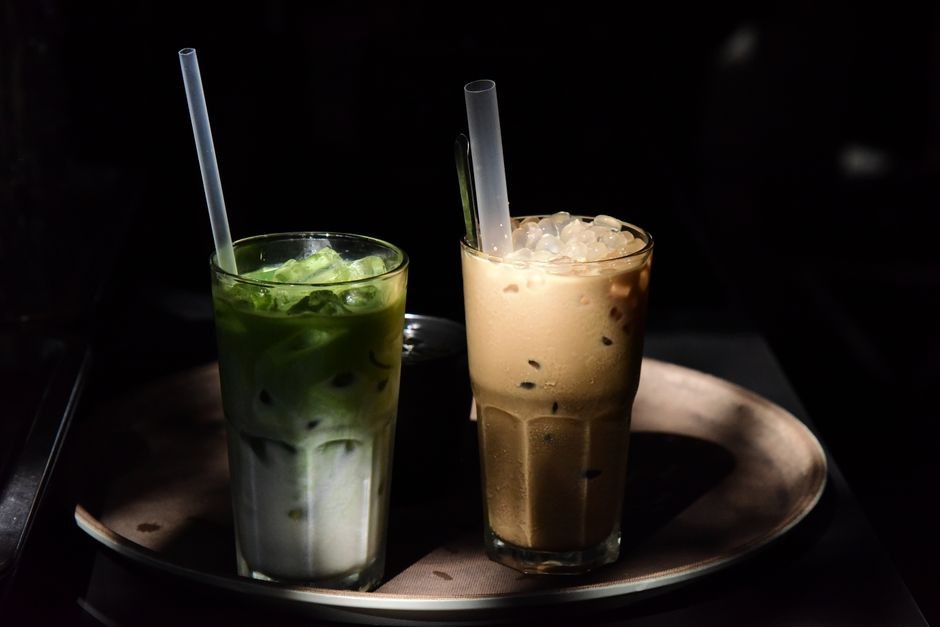 Gelas minuman susu teh kekinian berlabel artisan di atas meja