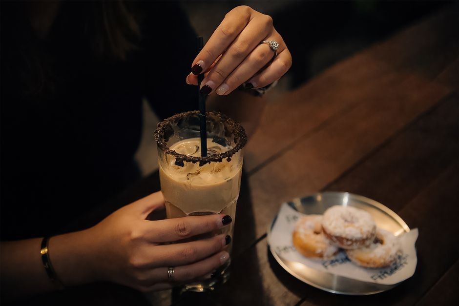 Tangan memegang gelas minuman kemasan sambil memeriksa labelnya