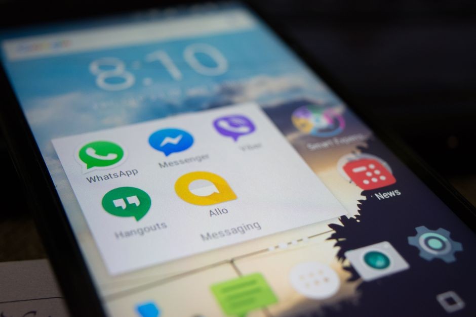 Tangan memegang ponsel yang sedang membuka percakapan Pesan Tersimpan WhatsApp