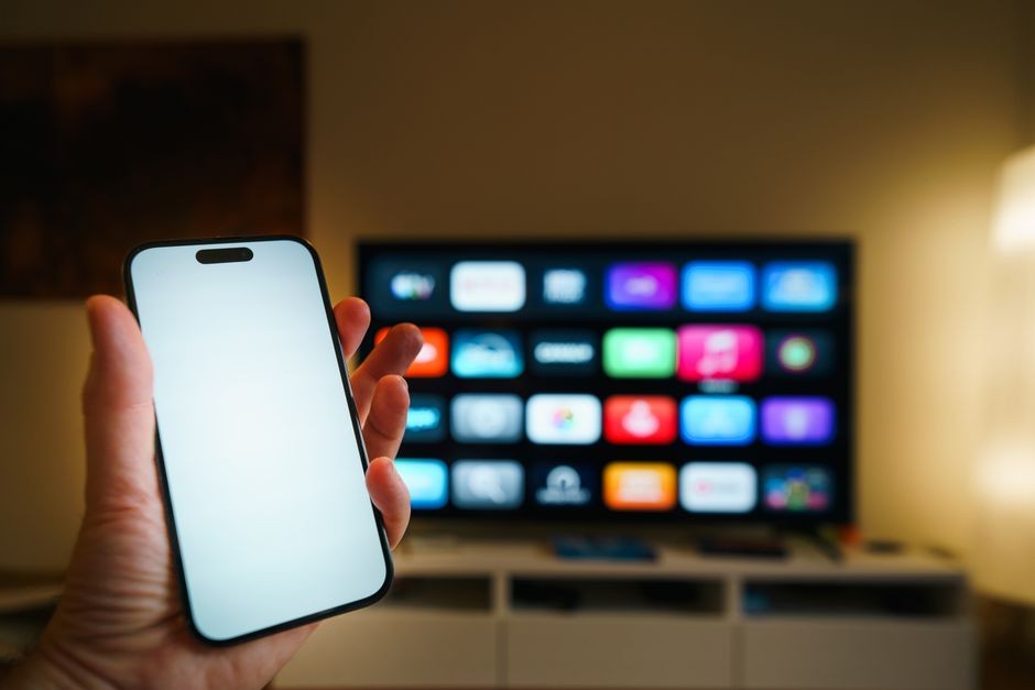 Remote smart TV dan ponsel Android di atas meja ruang tamu siap disambungkan nirkabel