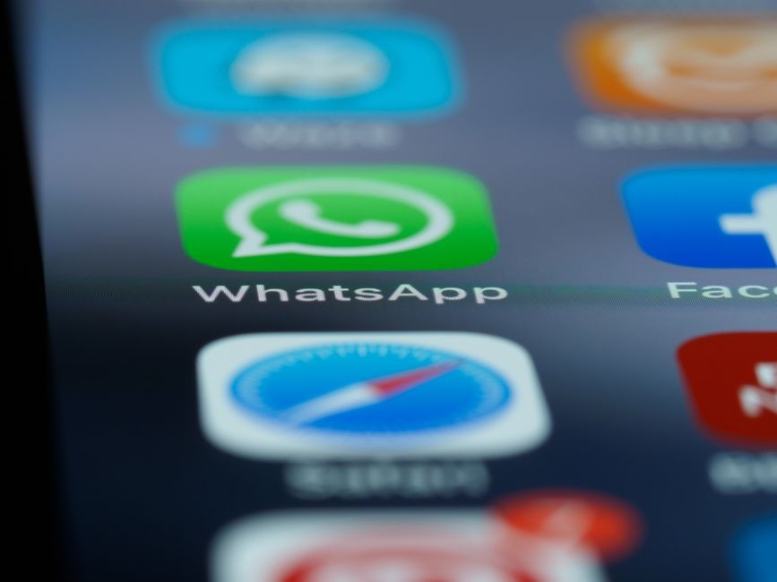 Layar smartphone menampilkan aplikasi pesan WhatsApp dengan beberapa obrolan terbuka.