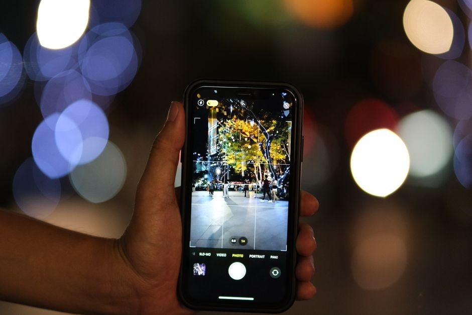 Tangan memegang smartphone di kamar gelap saat malam hari