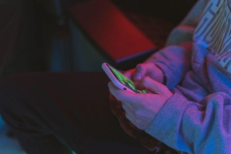 Tangan seseorang memegang ponsel saat bermain game mobile berat dalam waktu lama