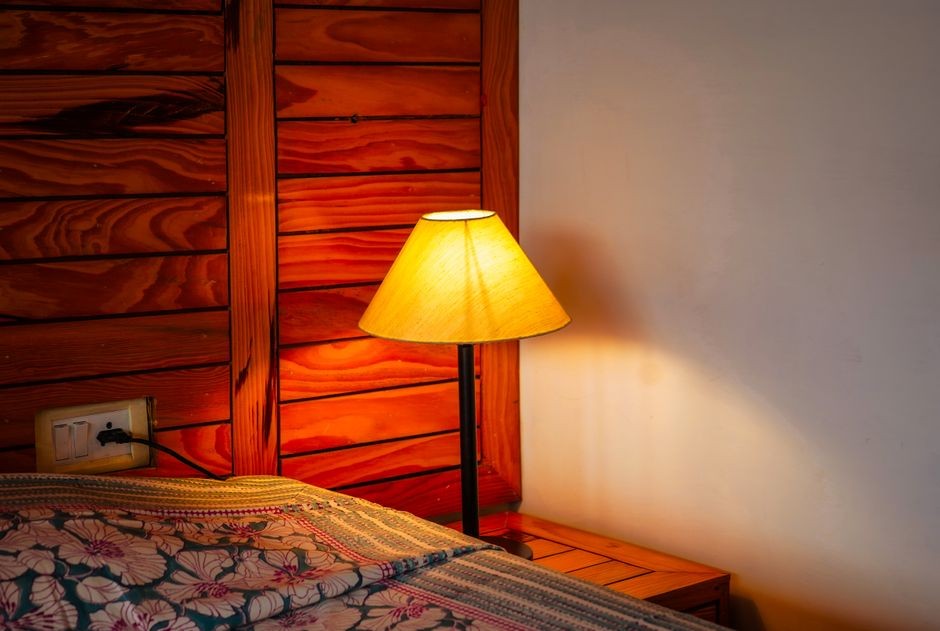 Lampu tidur menyala redup di meja nakas kamar, ilustrasi cahaya rendah yang tetap mengganggu produksi melatonin