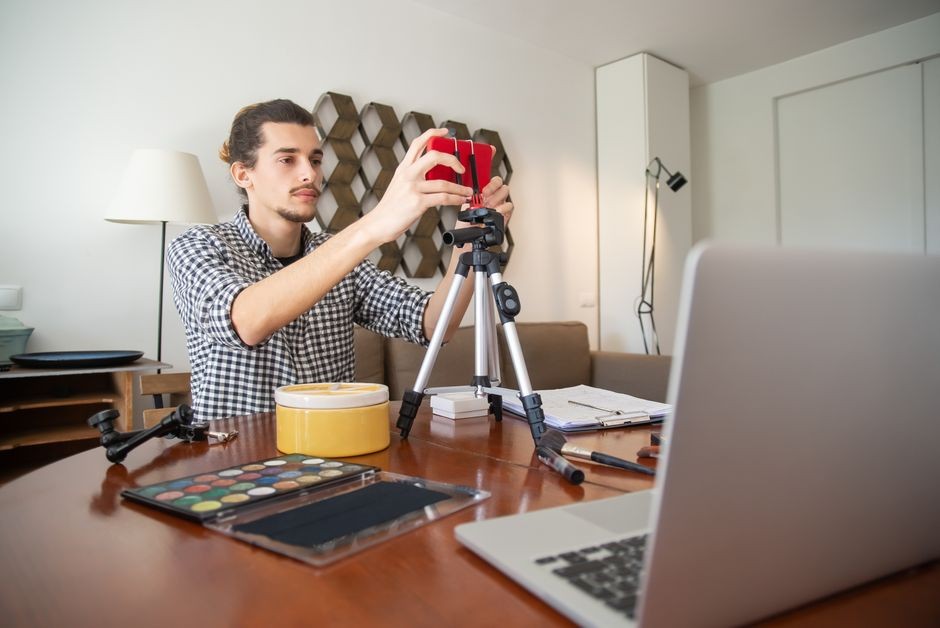 Ponsel dipasang pada tripod kecil di meja sebagai pengganti webcam laptop