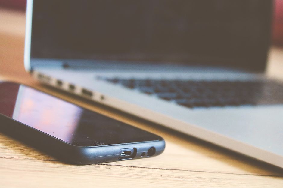 Meja kerja modern dengan laptop dan smartphone yang dipakai sehari-hari