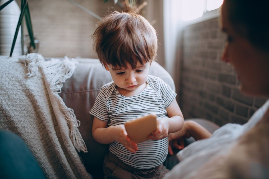 Cover: anak kecil sedang asyik bermain layar HP di dalam rumah