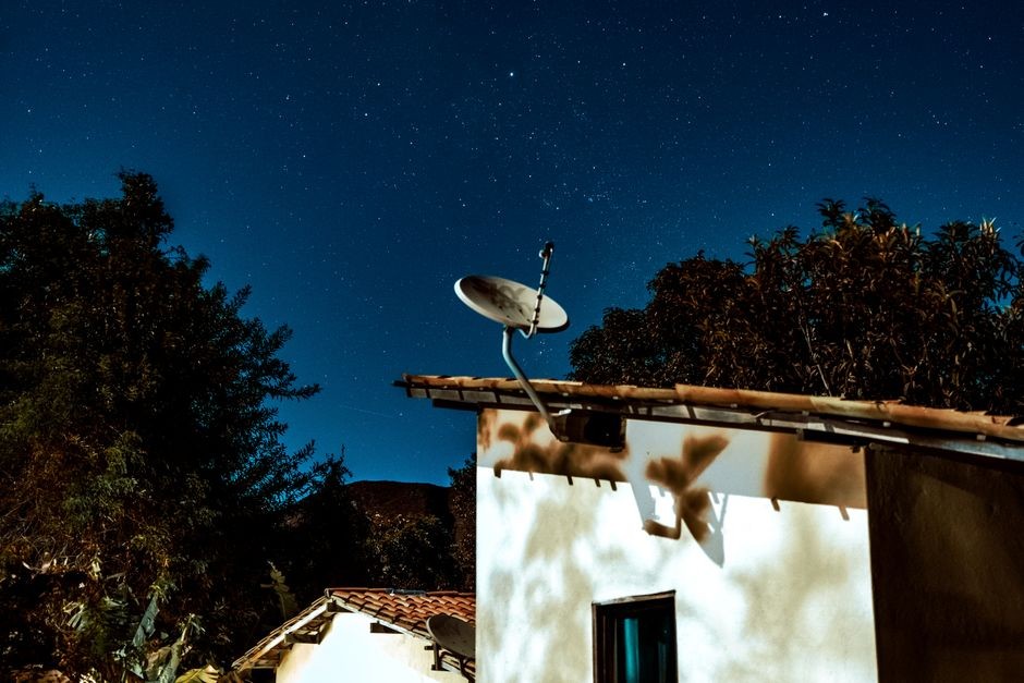 Ilustrasi antena parabola internet satelit dengan latar langit malam, melambangkan konektivitas dari orbit