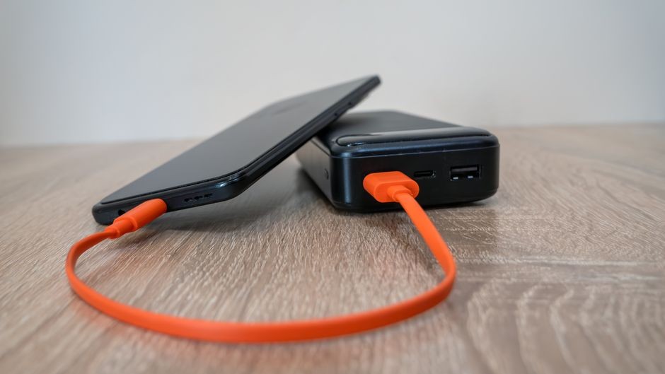 Ponsel pintar sedang terhubung dengan kabel pengisi daya power bank portabel