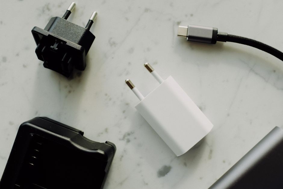 Smartphone sedang dicharge dengan kabel USB di stopkontak, layar menampilkan status pengisian daya