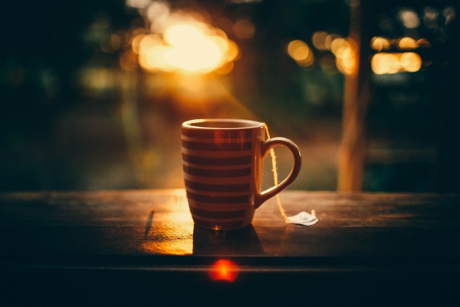 Cangkir kopi hitam di atas meja kayu, ilustrasi efek kopi terhadap risiko batu ginjal