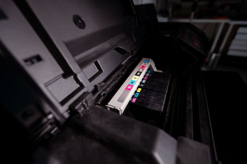 Printer ink tank rumahan duduk di meja kerja dengan tumpukan kertas A4 di sampingnya
