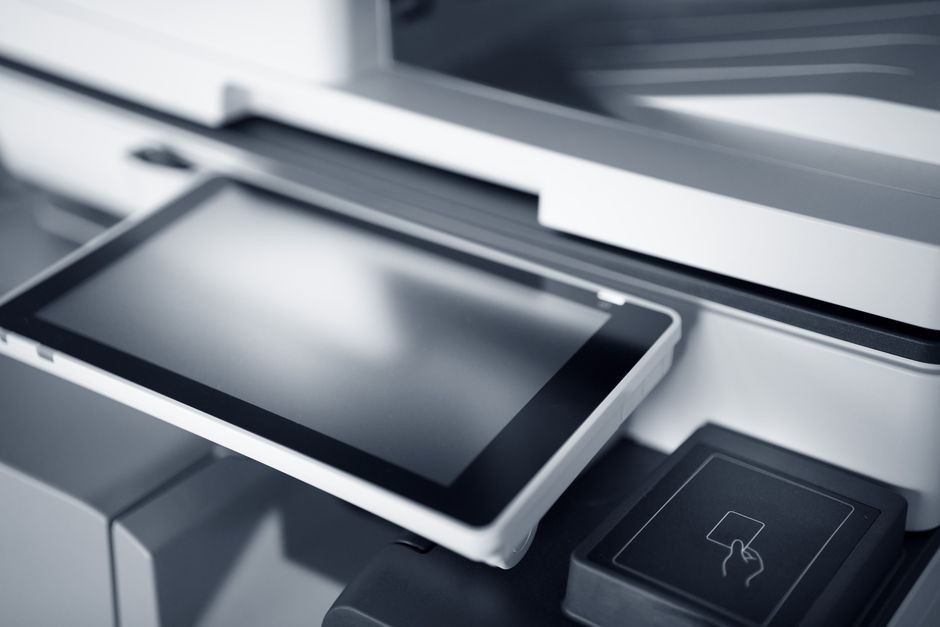 Tangan sedang mengeluarkan kertas yang tersangkut di mulut printer rumah