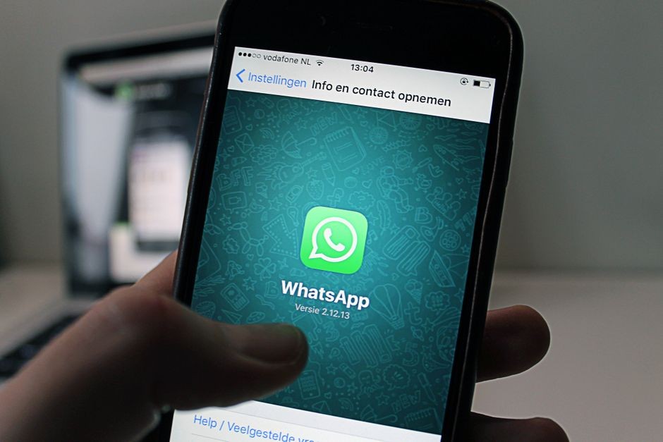 Seseorang memegang smartphone yang menampilkan antarmuka obrolan aplikasi WhatsApp di layar