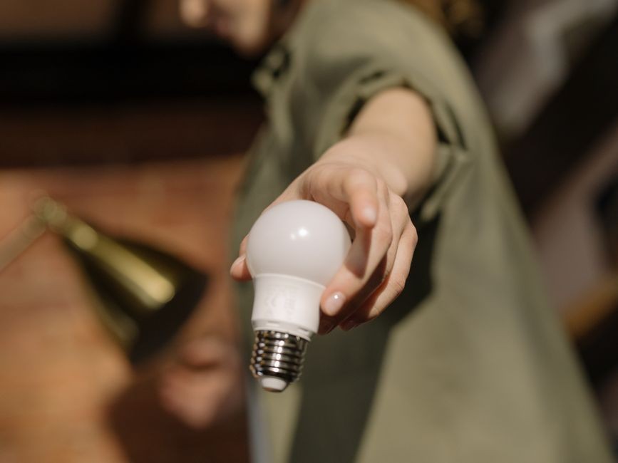 Tangan memasang bohlam LED ke dudukan lampu di plafon rumah, pemasangan sendiri harus memperhatikan jenis dudukan dan keamanan