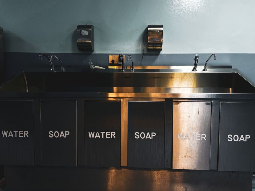 Kain serbet dapur sedang dicuci dengan air panas dan detergen di wastafel