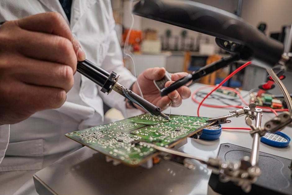 Teknisi profesional memeriksa jalur konektor mikro pada papan sirkuit smartphone di laboratorium