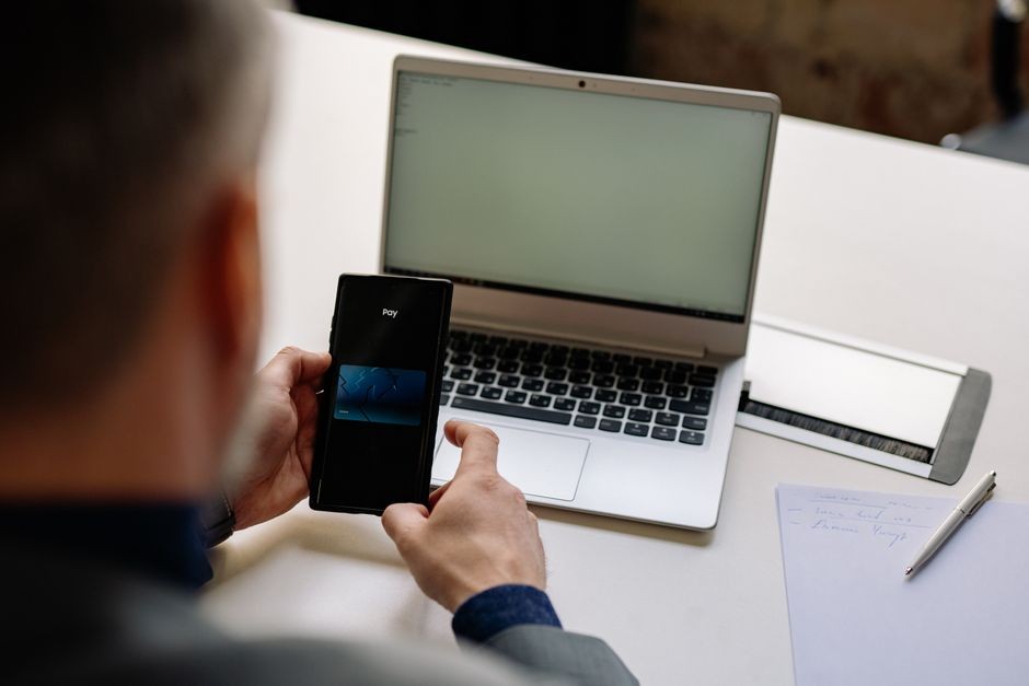 Layar aplikasi mobile banking terbuka pada ponsel yang tergeletak di atas meja kayu
