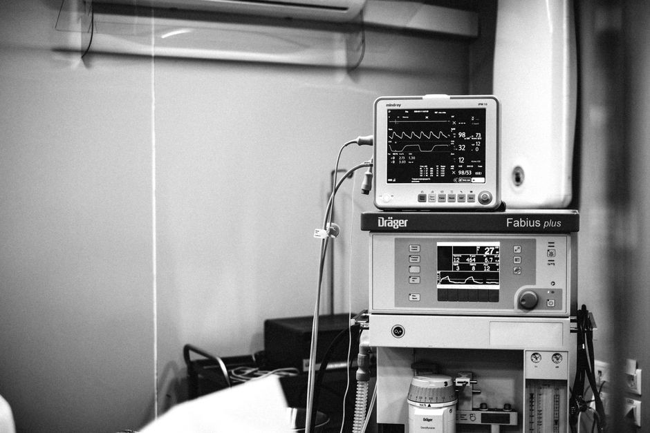 Pasien terbaring di ranjang unit perawatan intensif dengan monitor detak jantung di sampingnya