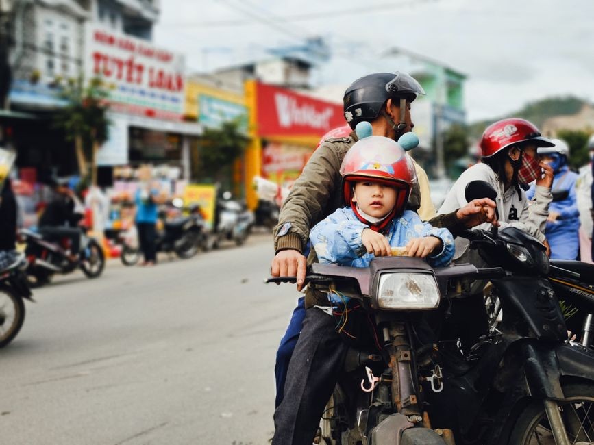 Anak kecil memakai helm motor saat dibonceng di belakang pengendara