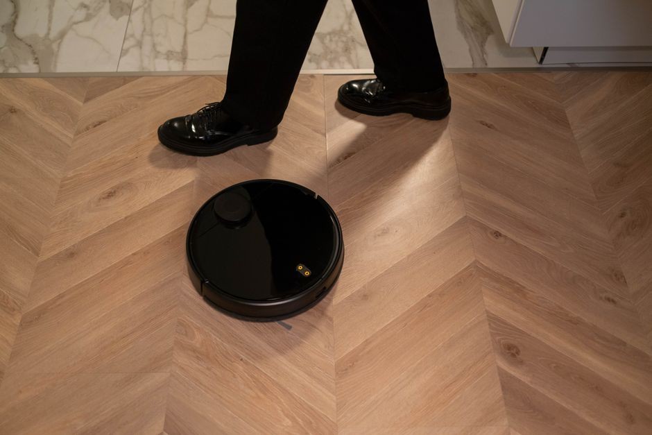 Robot penghisap debu sedang menyedot lantai dengan sensor menyala