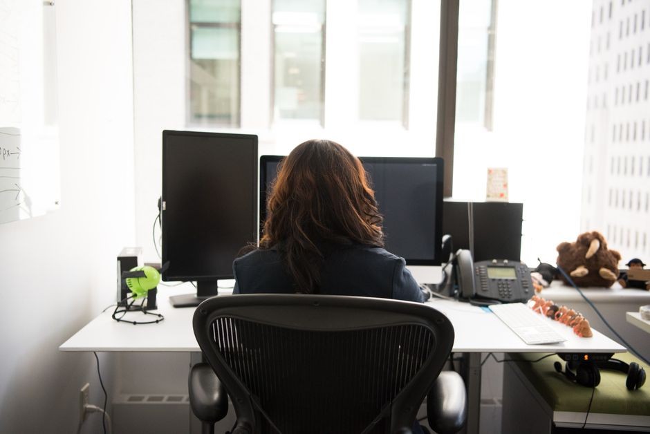 Pekerja kantor duduk di depan monitor dengan posisi layar sejajar pandangan