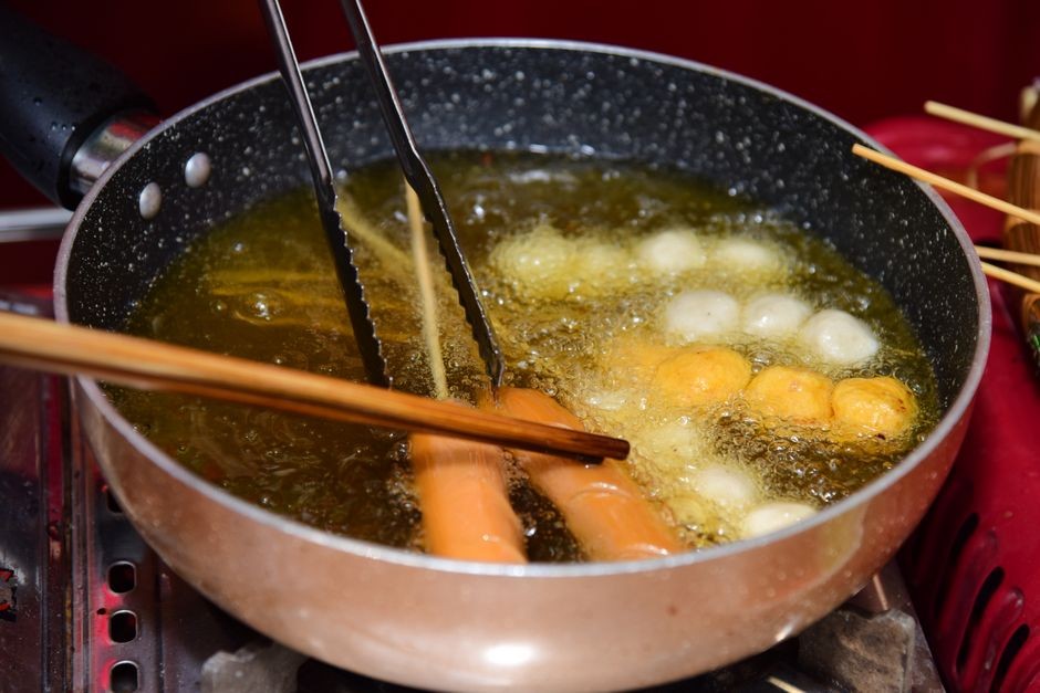 Makanan digoreng dalam minyak panas berbusa halus di dalam wajan dapur rumah tangga