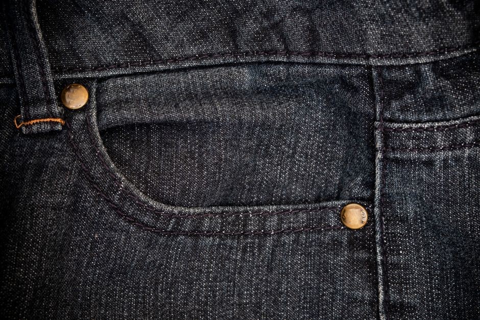 Detail ritsleting celana jeans denim dengan jahitan kain yang rapi