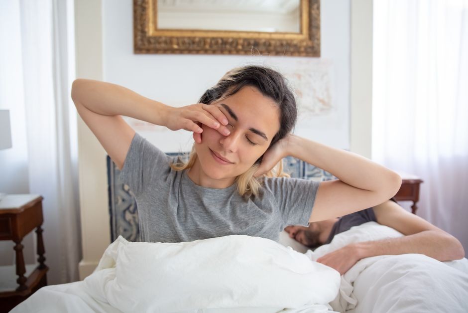 Seseorang bangun tidur dengan ekspresi lelah dan memegangi kepala karena pusing