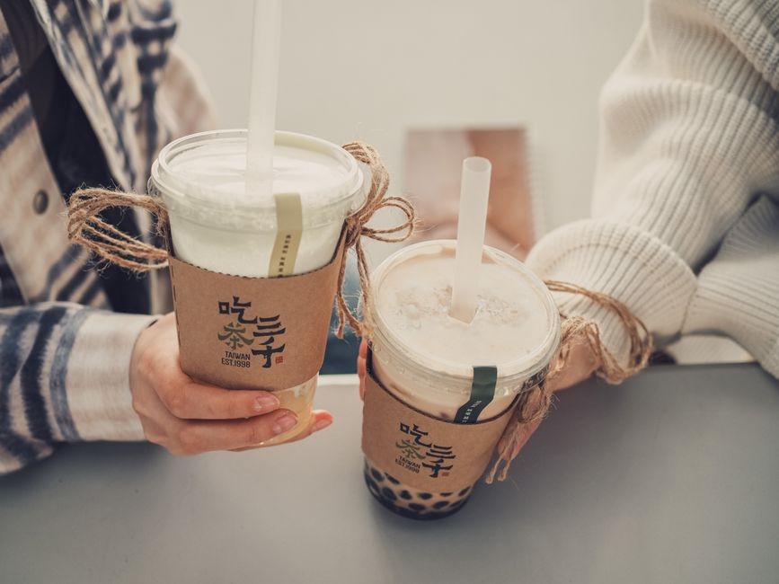 Segelas minuman manis boba kekinian dengan es batu dan sedotan di atas meja