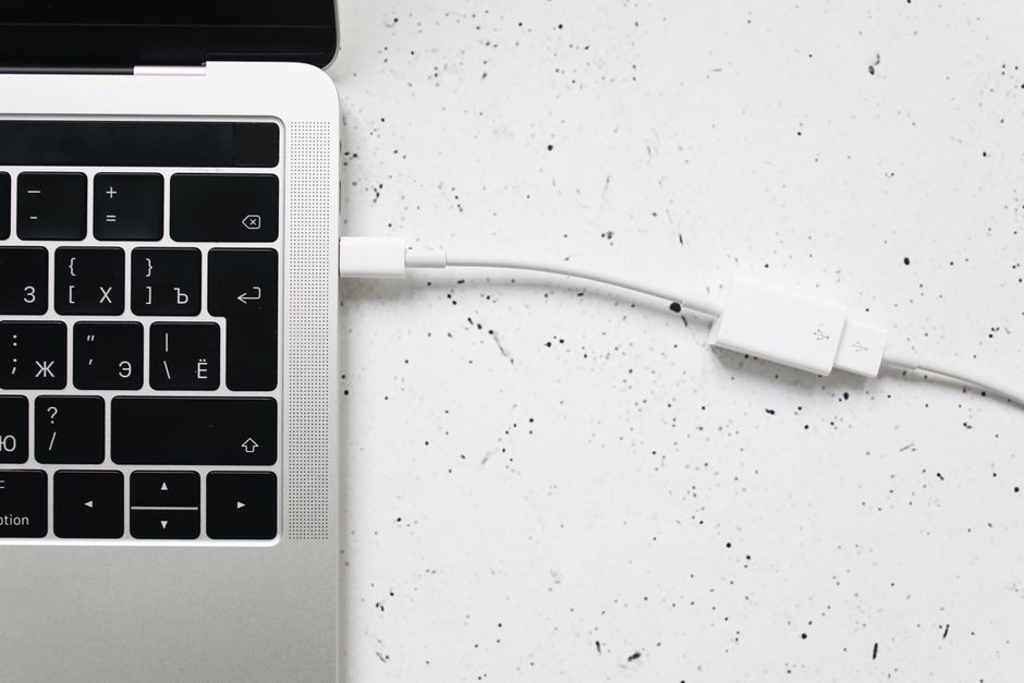 Seseorang menancapkan konektor kabel USB-C ke samping laptop untuk transfer data