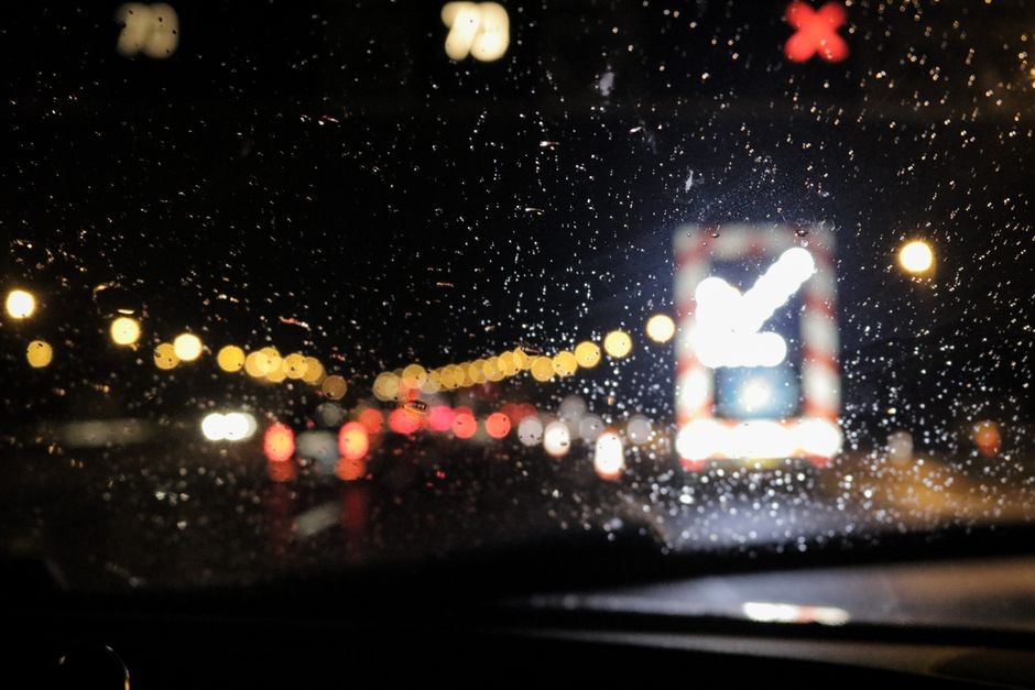 Pandangan pengemudi terganggu kilauan cahaya lampu jalan dan tetesan air di kaca mobil