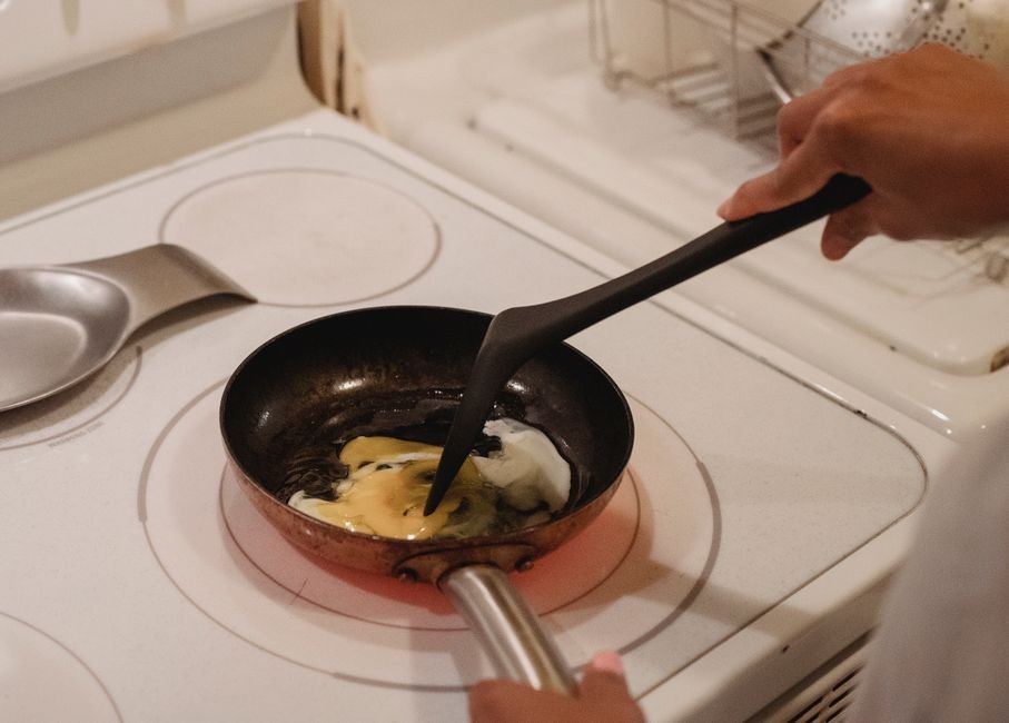 Memasak hidangan di atas wajan penggorengan menggunakan spatula kayu pelindung agar lapisan tidak tergores