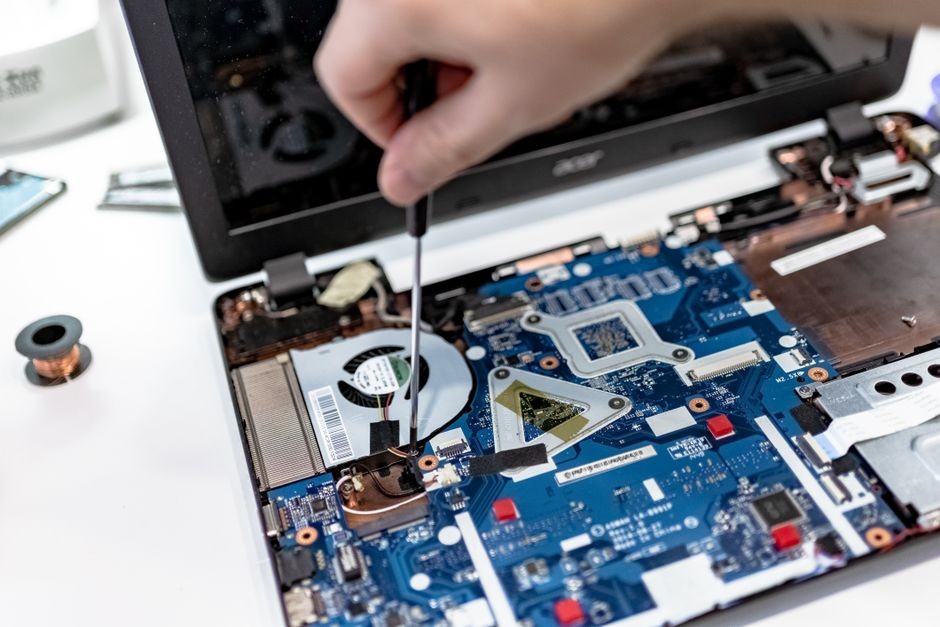 Tangan teknisi memperbaiki komponen internal laptop menggunakan obeng presisi
