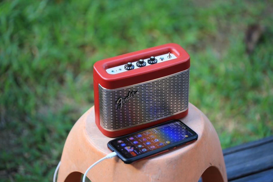Seseorang memutar audio pada smartphone dengan posisi speaker menghadap luar di ruangan santai