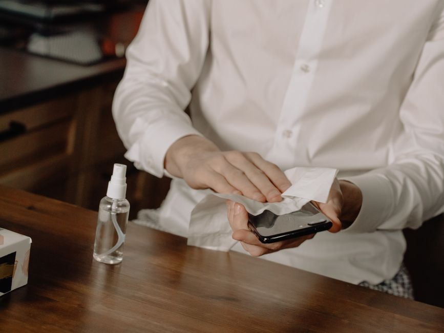 Membersihkan kaca layar sentuh smartphone menggunakan kain khusus agar bebas kotoran